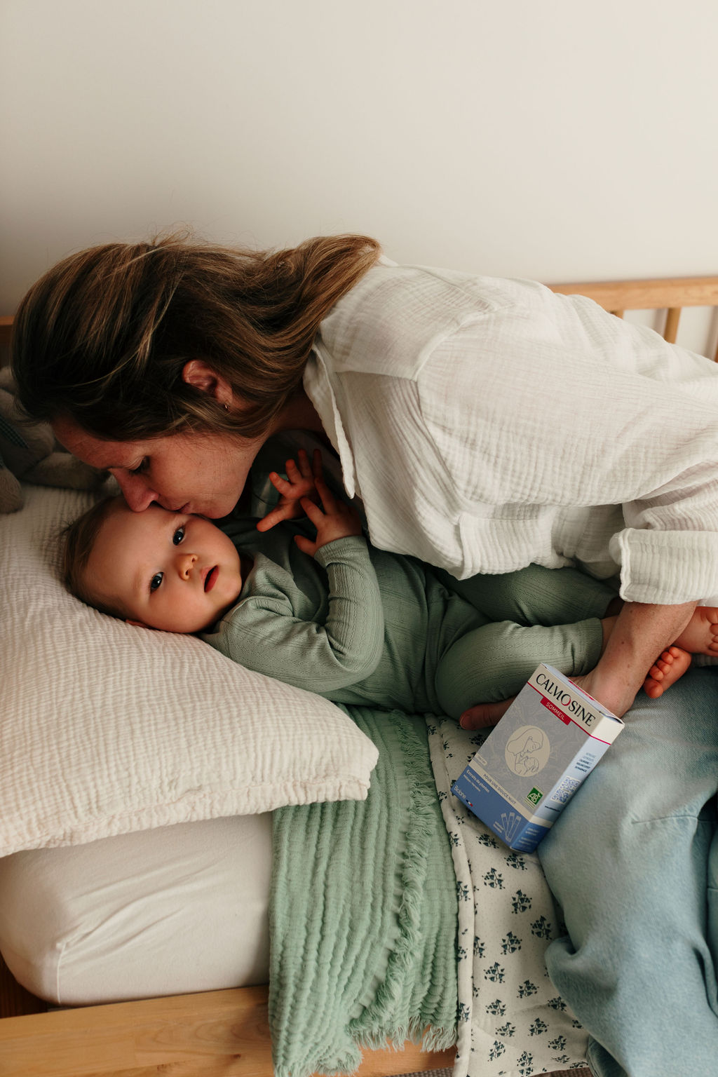 Maman faisant un baiser à son bébé dans son lit avec Calmosine Sommeil
